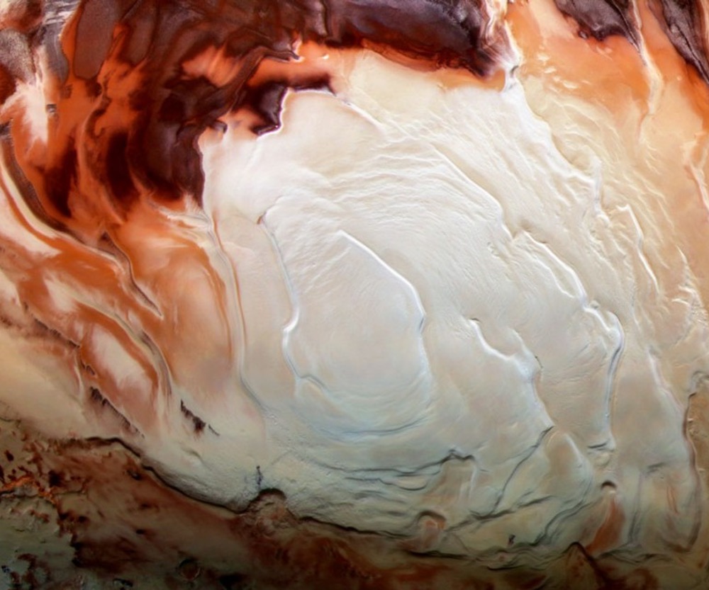 Mars’ south pole – which looks like creamy swirls in cappuccino – is an icy cap with carbon dioxide and other geologic traits.  About a mile below the cap is smectite, a hydrated version of clay
